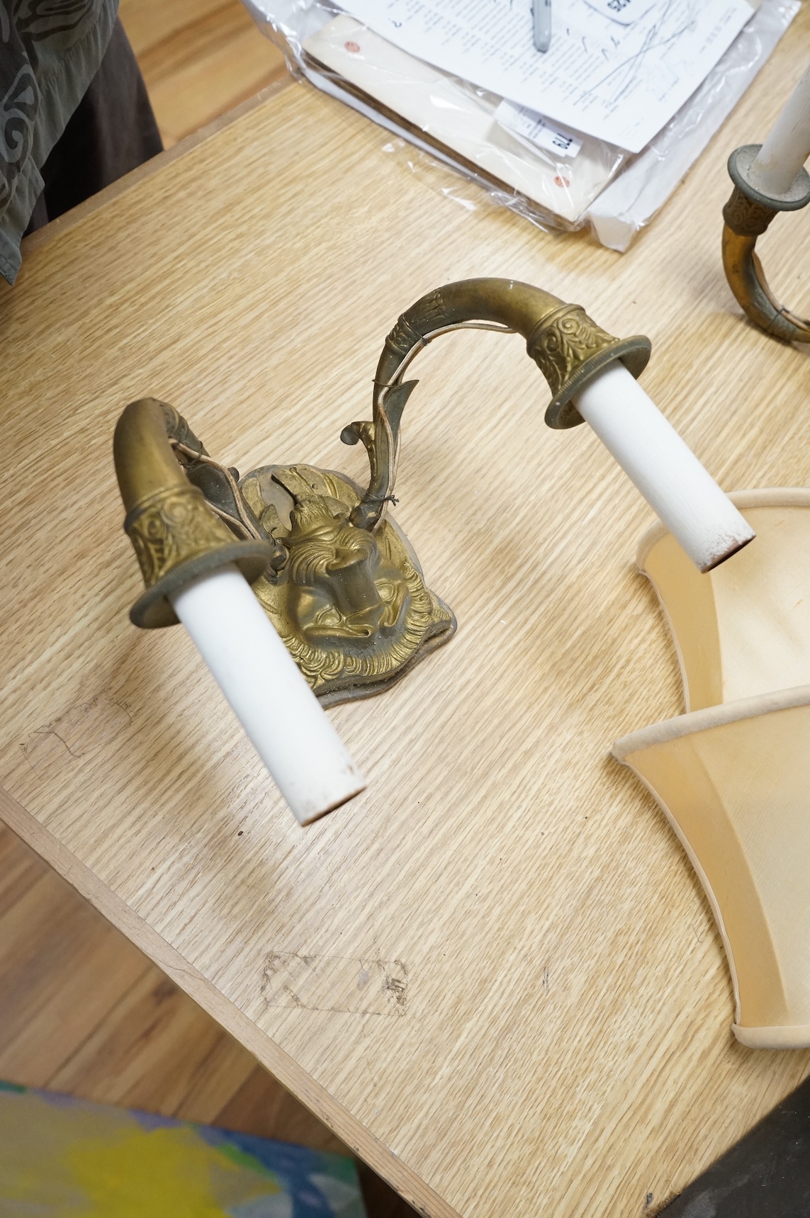 A pair of ‘lion mask’ gilt metal two branch wall sconces and four silk shades, 22cm wide